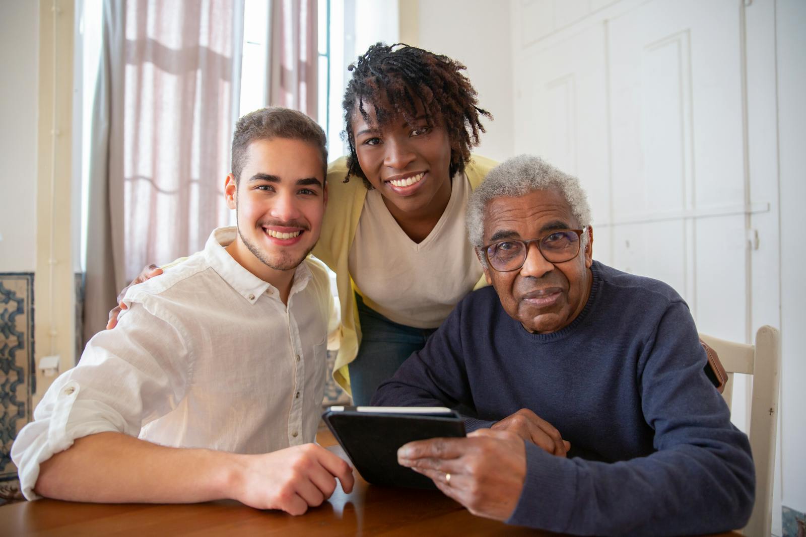 Un senior utilisant sa tablette en présence de ses aidants