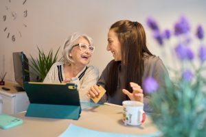 Femme senior et sa fille entrain de rire devant une tablette